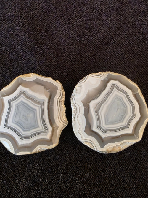 Matched pair of Lebanese banded agate geode halves from Minieh shore, showing crisp octagonal concentric banding in gray, white, and cream.
