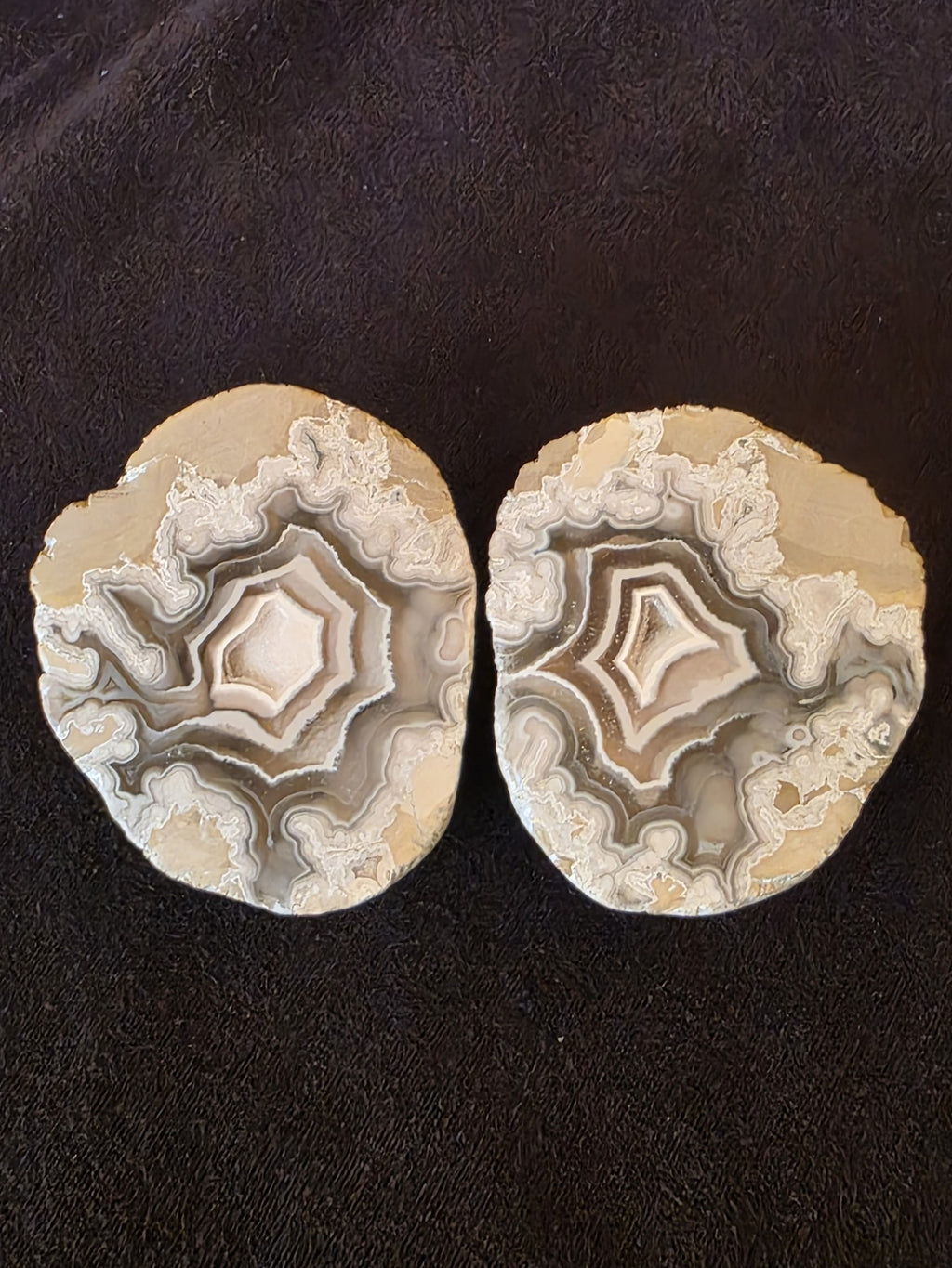 Close-up of both polyhedral agate geode halves showing matched concentric diamond and pentagonal chamber patterns.
